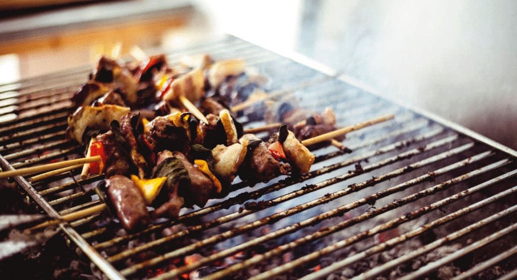 A grill with some meat and mushrooms on it